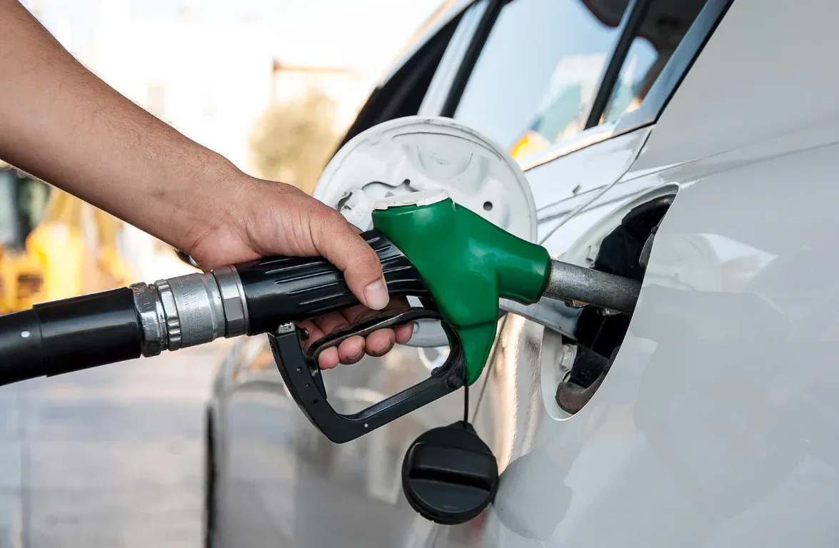 A hand holds a green fuel nozzle, refueling a white vehicle, representing fuel tax credits optimisation for fleet management.