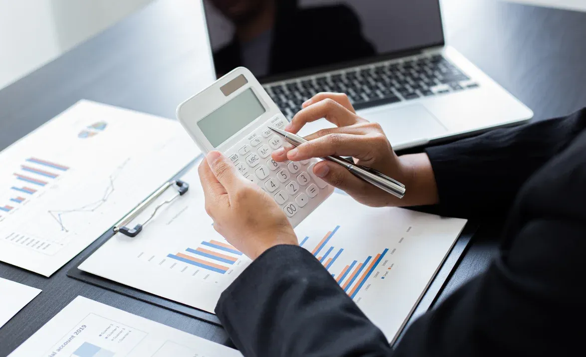 A business professional uses a calculator while reviewing financial reports and charts, representing fuel tax credits optimisation.